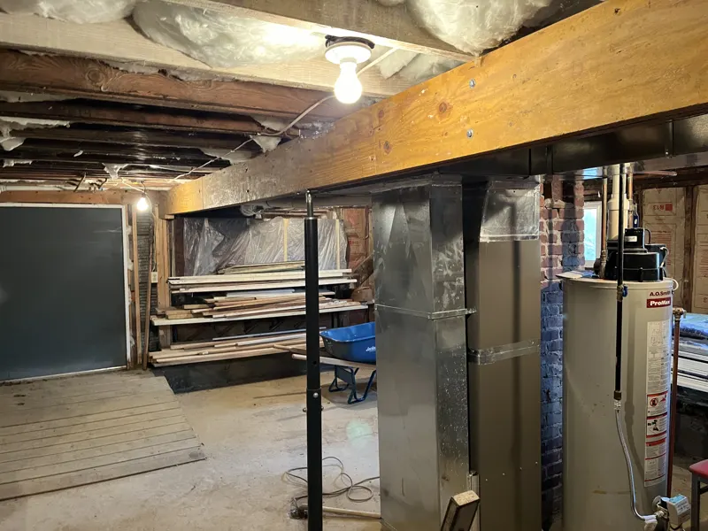 Unfinished basement with a steel support post under a wood beam