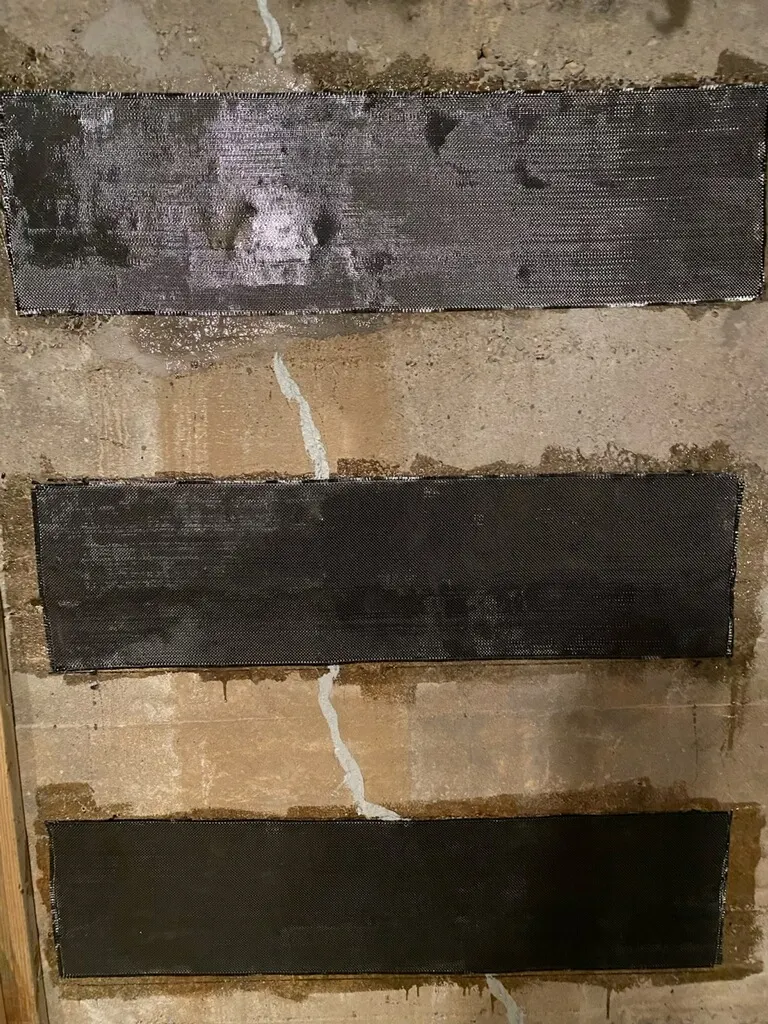 Three horizontal carbon fiber strips bonded across a crack in a poured concrete wall