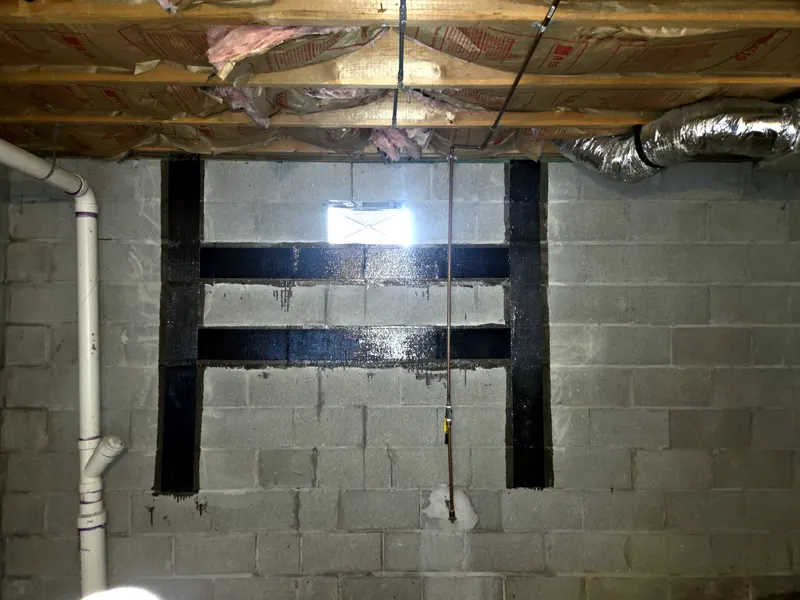 Vertical and horizontal carbon fiber straps on a block basement wall around a basement window